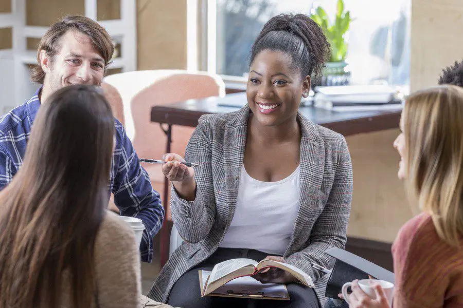 Woman smiling at the center of a casual group discussion.