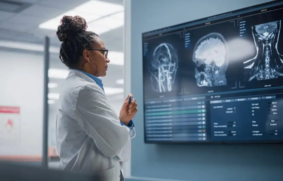 Female doctor analyzing brain scan on televised display.