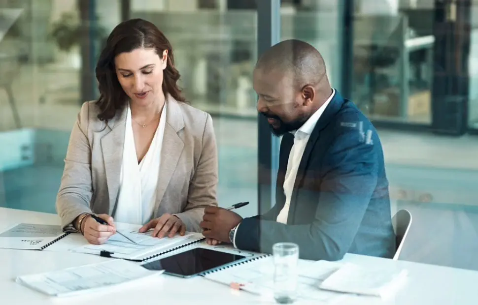 Two professionals reviewing documents during their discussion.