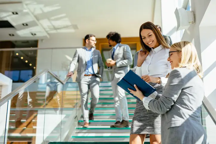 Group of professionals walking and talking on a glass staircase.