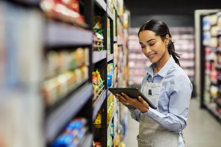 Young woman using tablet in supermarket workplace