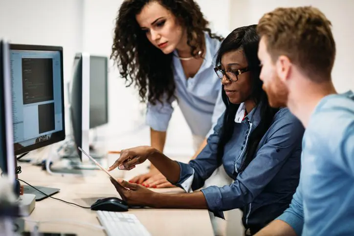 Team of diverse coworkers collaborating around a desktop computer.